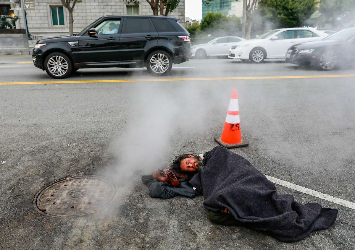 Homeless man Kevin Christopher Highfield, 39, tries to rest in a parking spot on Larkin Street as cars pass by him in San Francisco, California, on Tuesday, June 18, 2019. Kevin said he has been homeless since he was 18 years old after getting kicked out of the house by his mother. He broke his left leg and it never properly healed so it causes him great pain. Photo taken on Larkin Street between McAllister and Fulton Streets at 6:46pm
