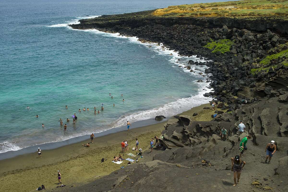 In this photo taken July 7, 2014, people sunbathe at Papakolea green sand beach near Ocean View, Hawaii. Online auction and sales company eBay has removed multiple listings of sand said to be taken from Hawaii beaches. The Hawaii Tribune-Herald reported Saturday, Nov. 4, 2017, that it asked the company about the listings before they were taken down. Among them was a listing claiming to have sand from Papakolea Beach, also known as Green Sands Beach. (AP Photo/Marco Garcia)