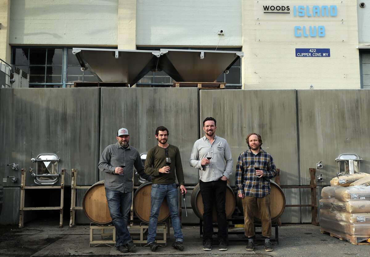 The crew at Wood's Island Club, l-r, Chris Scanlan, consulting winemaker, Kyle Jeffrey, assistant winemaker, Jim Woods, founder and CEO, and Kim Sturdavant, head brewer, in front of the concrete wine tanks on Treasure Island in San Francisco, Calif., on Tuesday, December 10, 2019. A new state law in California, takes effect Jan 1, that will allow wineries, breweries and distilleries to have overlapping licenses. Woods Beer Co. is now also making wine at its Treasure Island facility.