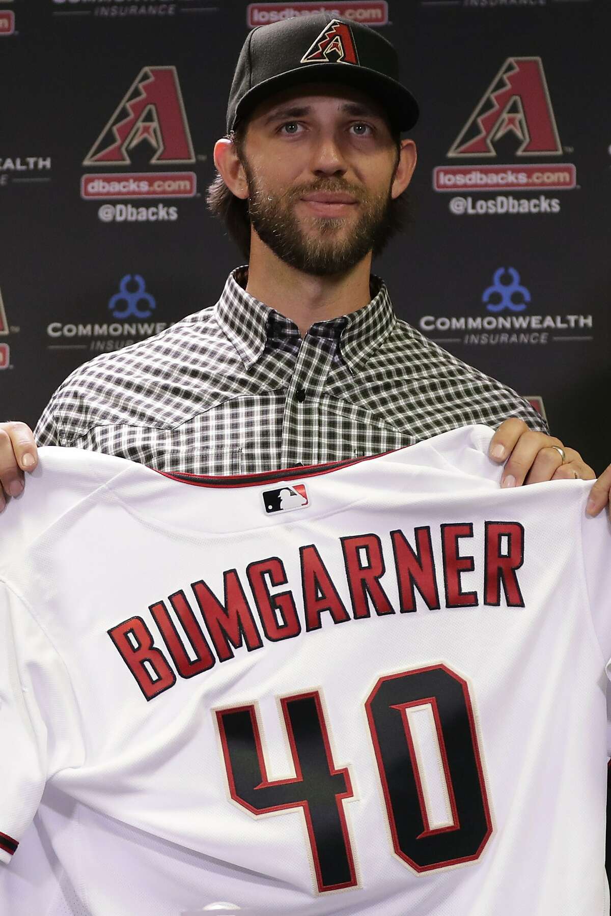 Newly acquired Arizona Diamondbacks pitcher Madison Bumgarner holds his new jersey after being introduced during a team availability, Tuesday, Dec. 17, 2019, in Phoenix. (AP Photo/Matt York)