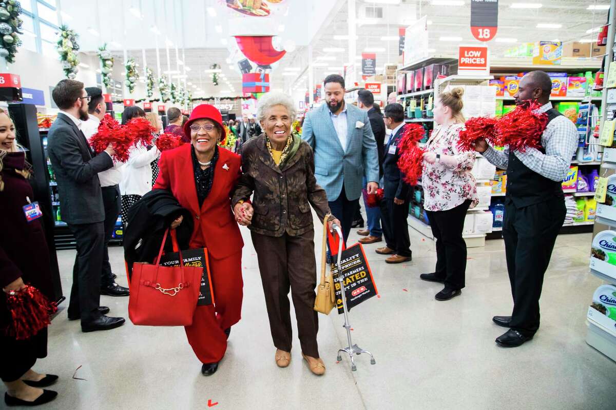 Lillie Lockett, who is “over 70” and her next door neighbor Eva Harvey, 90, hold hands as they walk in between two lines of HEB employees cheering for the members of the Third Ward community as they enter the new HEB store on MacGregor on Tuesday, Dec. 17, 2019, in Houston. Lockett has been a Third Ward resident for more than 25 years and Harvey has been a resident for more than 50 years.