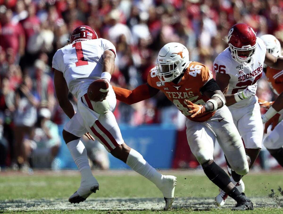 DALLAS, TEXAS - OCTOBER 12: Jalen Hurts #1 of the Oklahoma Sooners tucks the ball behind his back as he avoids the tackle against Joseph Ossai #46 of the Texas Longhorns during the 2019 AT&T Red River Showdown at Cotton Bowl on October 12, 2019 in Dallas, Texas. (Photo by Ronald Martinez/Getty Images)