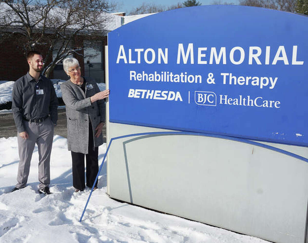 Daniel Vogel, administrator, and Hazel Morgan, referral coordinator, watch as the new Alton Memorial Rehabilitation & Therapy sign is installed outside the former Eunice Smith Home on Tuesday, Dec. 18.