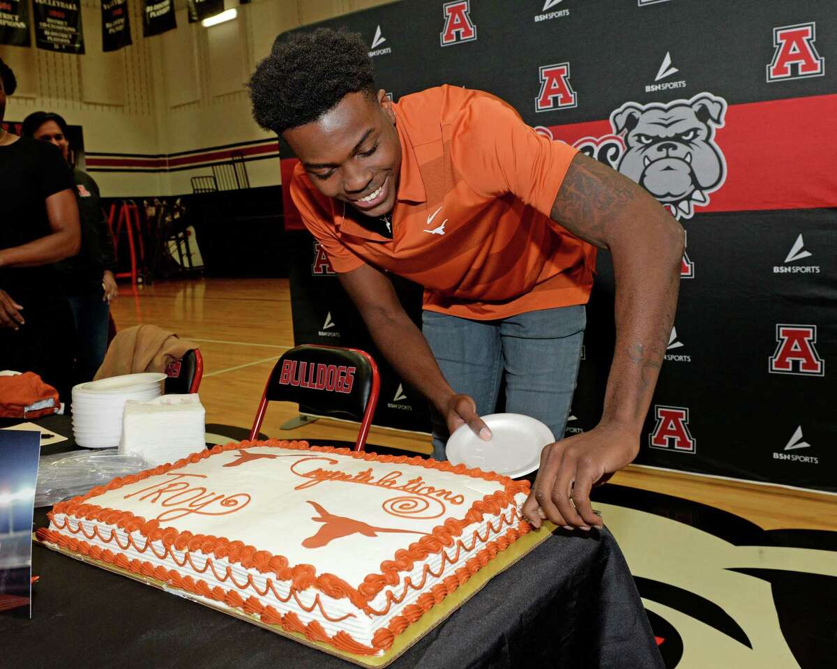 Troy Omeire of Fort Bend Austin cuts a cake after signing to play for the University of Texas.