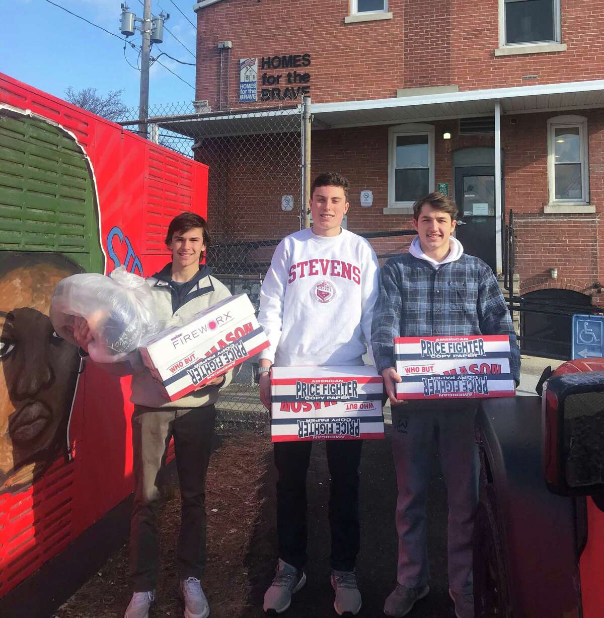Socks for Soldiers program coordinators Connor Burke, left, Jack Savarese and Jake Zeyher deliver their Christmas collection of socks to Homes for the Brave in Bridgeport on Dec. 19.