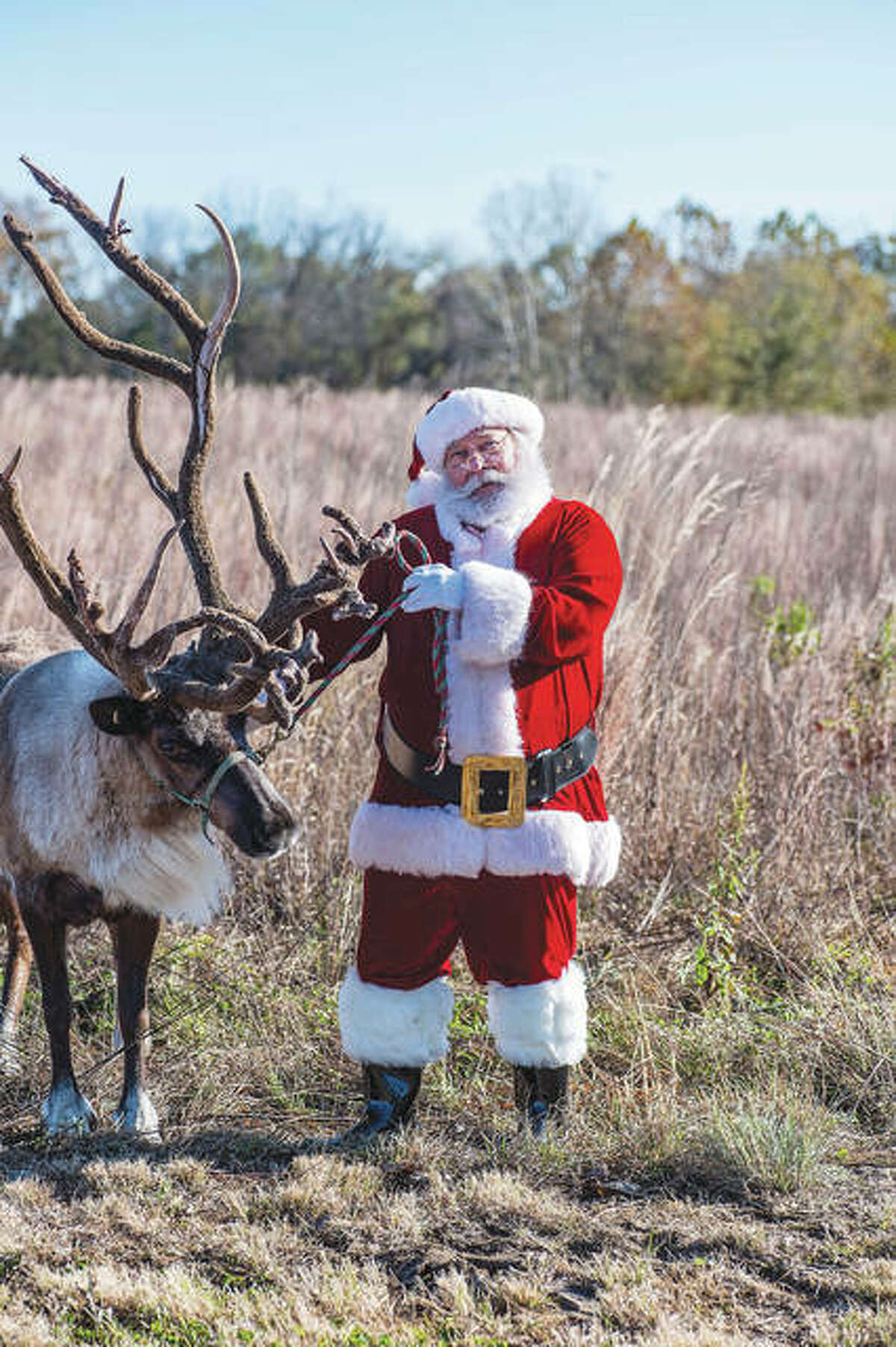 Santa’s “cousin,” Steve Pegram, shares a moment with a reindeer during a holiday photo shoot in Jersey County. Pegram tells children there’s only one Santa, but St. Nick has many cousins.