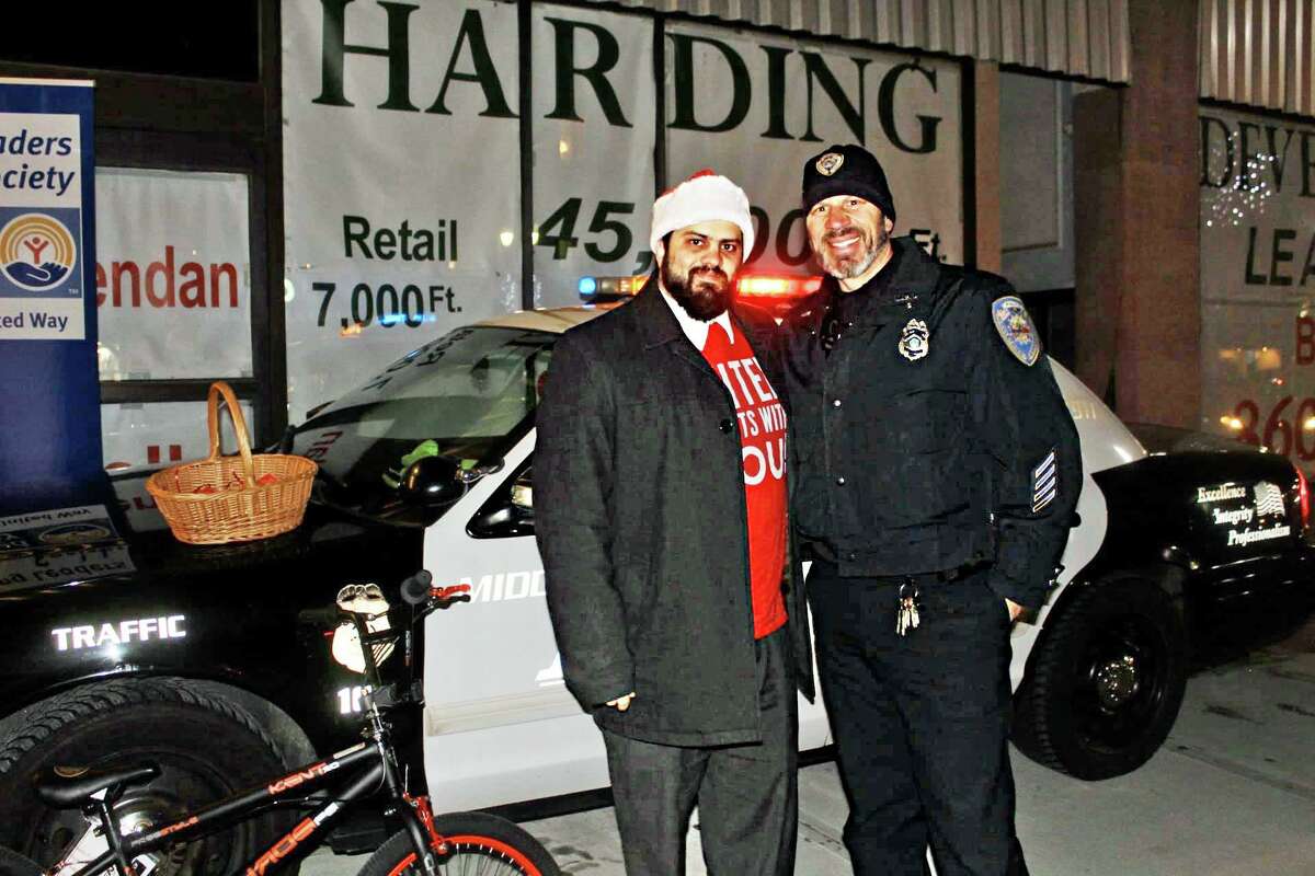 The Middlesex United Way Young Leaders Stuff-a-Cruiser holiday social and toy drive in Middletown gathered hundreds of gifts for local teens. From left are Kevin Harris of Chester, chairman of the Young Leaders Society, and Middletown Police Officer Anthony Knapp.