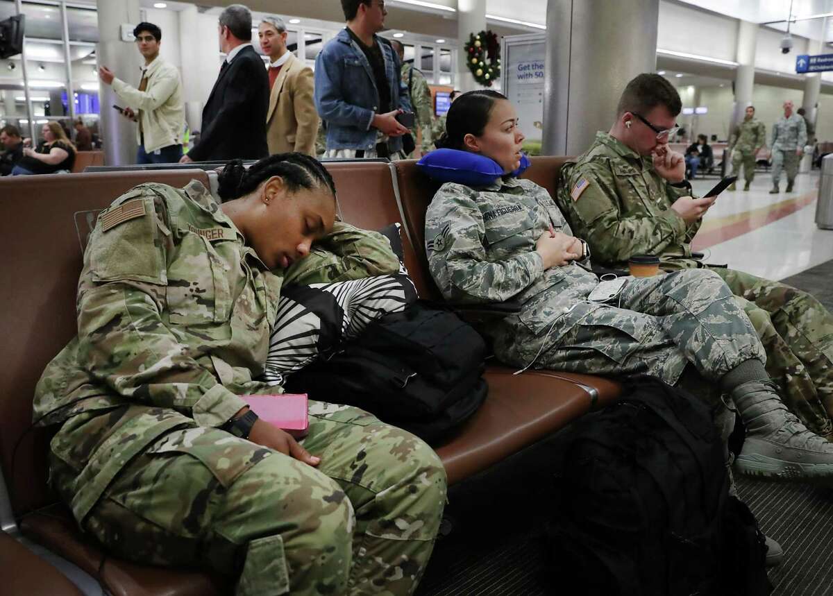 A U.S. Army soldier, left, sleeps while waiting for a flight with other military personnel as Mayor Ron Nirenberg walks past while visiting troops on their way home. Thousands of soldiers, sailors and airmen hit the San Antonio International Airport early Friday morning to catch commercial flights home for the holidays.