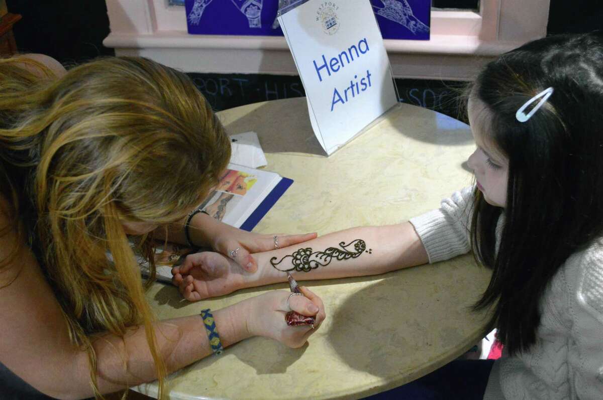 Westporter Christina Dear, left, does some henna work on Tessa Balmer, 9, of Westport, at last year’s First Light Festival. The event returns this year at the Westport Museum and other locations in town.