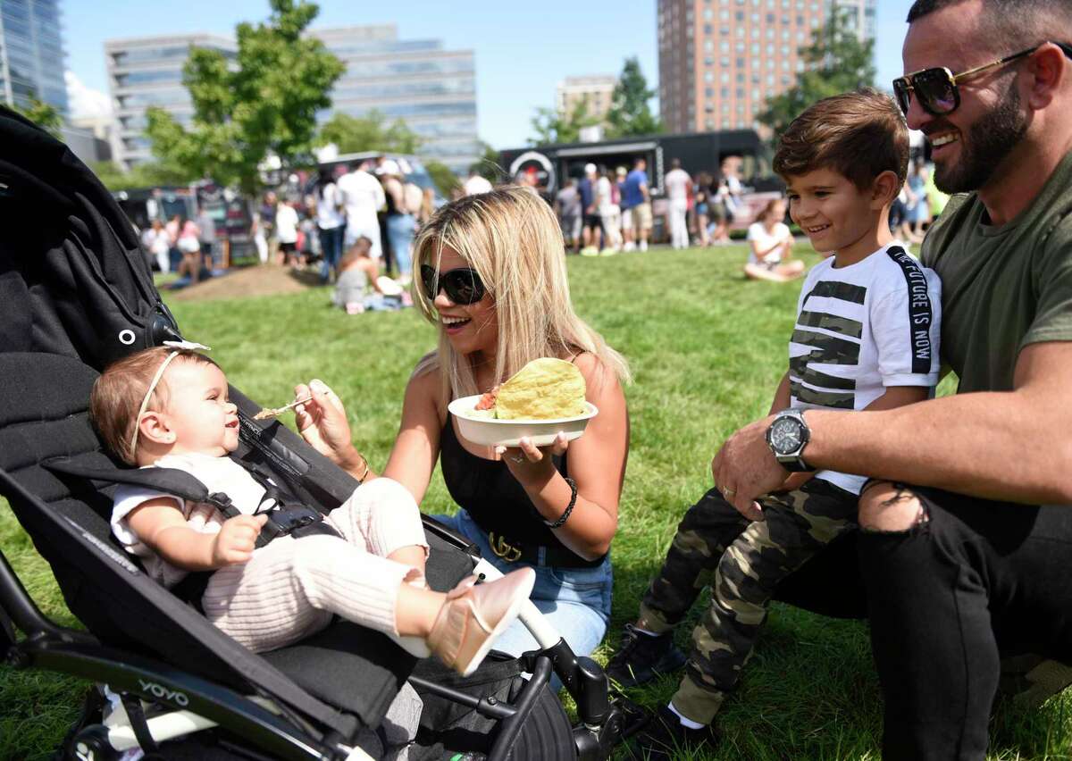 Danbury couple Tatiana and Val Mehmeti eat food from Rice & Beans with their children Luna, 10 months, and London, 5, at the Hey Stamford! Food Festival at Mill River Park in Stamford, Conn. Sunday, Aug. 25, 2019. The two-day event, now in its third year, featured dozens of local food vendors as well as beer, children's games, and live music.