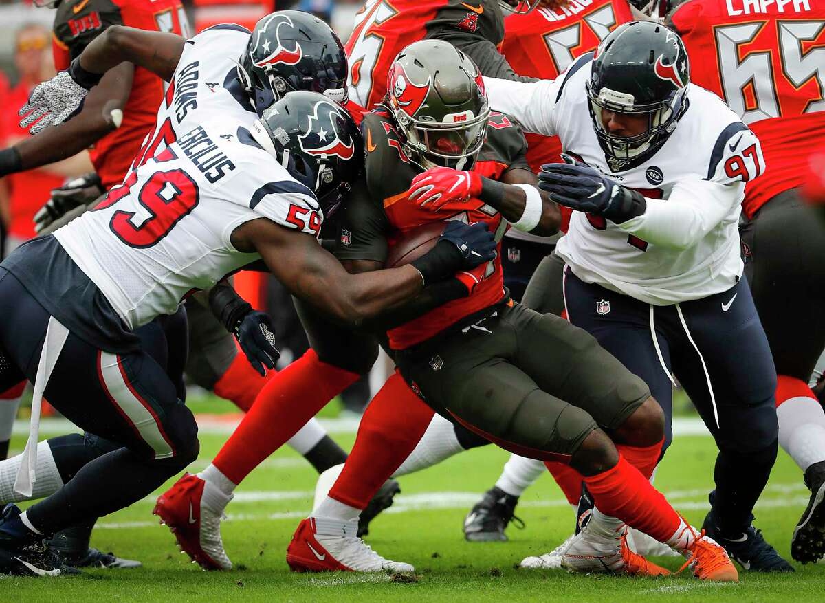 Houston Texans defensive end Angelo Blackson (97) and outside linebacker Whitney Mercilus (59) stop Tampa Bay Buccaneers running back Ronald Jones (27) for a loss during the first quarter of an NFL football game at Raymond James Stadium on Saturday, Dec. 21, 2019, in Tampa.