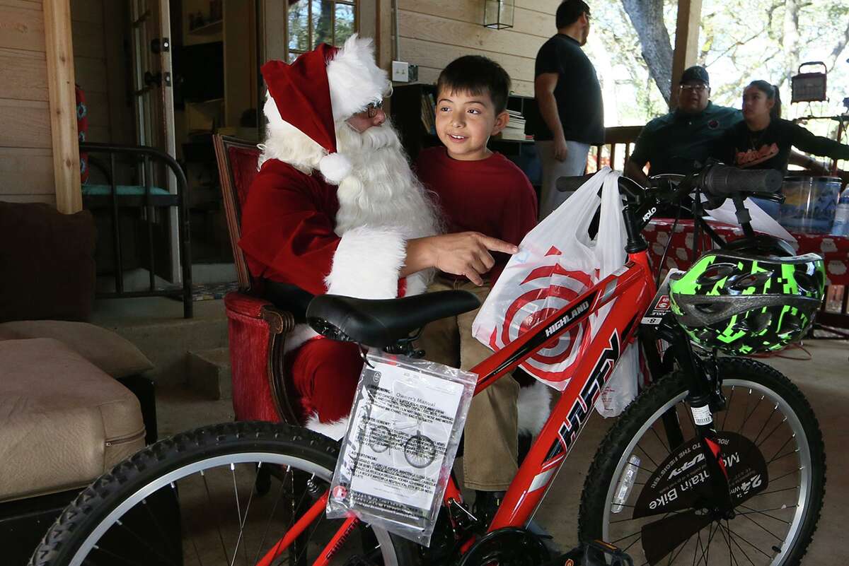 Enrique Perez, 8, receives a bicycle from Santa Claus during a Christmas party with Santa hosted by Pamela Allen at her home in Boerne on Saturday, Dec, 14, 2019. Allen, a co-founder of Eagles Flight Ministries, has advocated for a wide range of people that have included refugees, children with special needs and the homeless for the past 28 years.