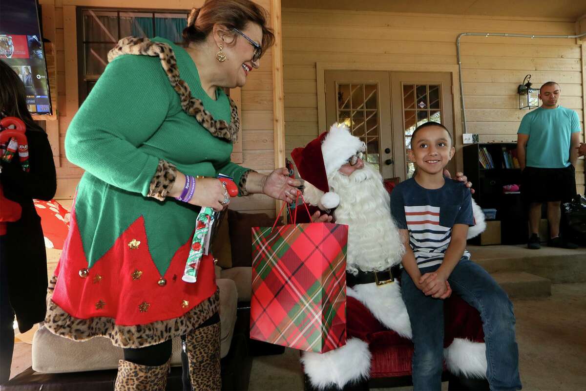 Jamel Rodriguez, 8, receives presents from Santa Claus and Pamela Allen, left, during a Christmas party with Santa hosted by Allen at her home in Boerne on Saturday, Dec. 14, 2019. Allen, a co-founder of Eagles Flight Ministries, has advocated for a wide range of people that have included refugees, children with special needs and the homeless for the past 28 years.