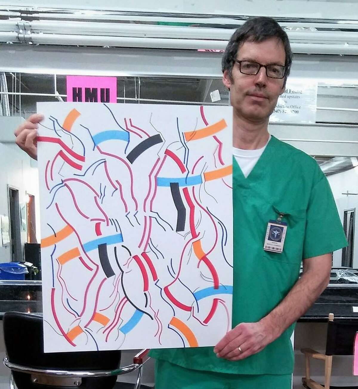 Artist Darien Robert Carley holds an abstract drawing he created while working as an extra on a medical TV show.