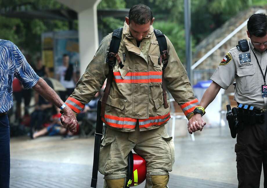 A firefighter holds hands with others during a prayer before the Memorial Tower Climb at the Tower of Americas in commemoration of Sept. 11, 2001. Photo: Bob Owen/Staff Photographer