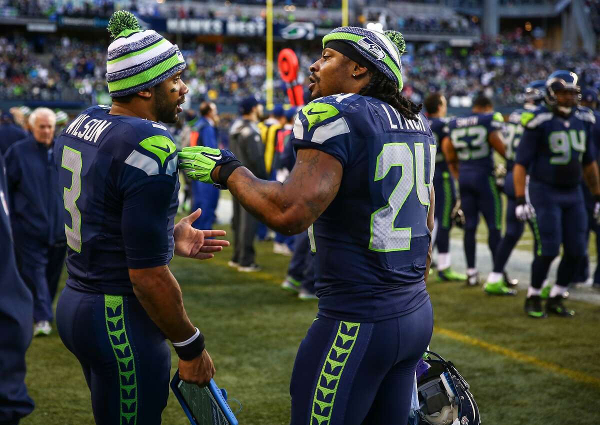 Seattle Seahawks players Marshawn Lynch and quarterback Russell Wilson talk on the sidelines during play against the San Francisco 49ers at CenturyLink Field in Seattle. Photographed on Sunday, December 14, 2014. (Joshua Trujillo, seattlepi.com)