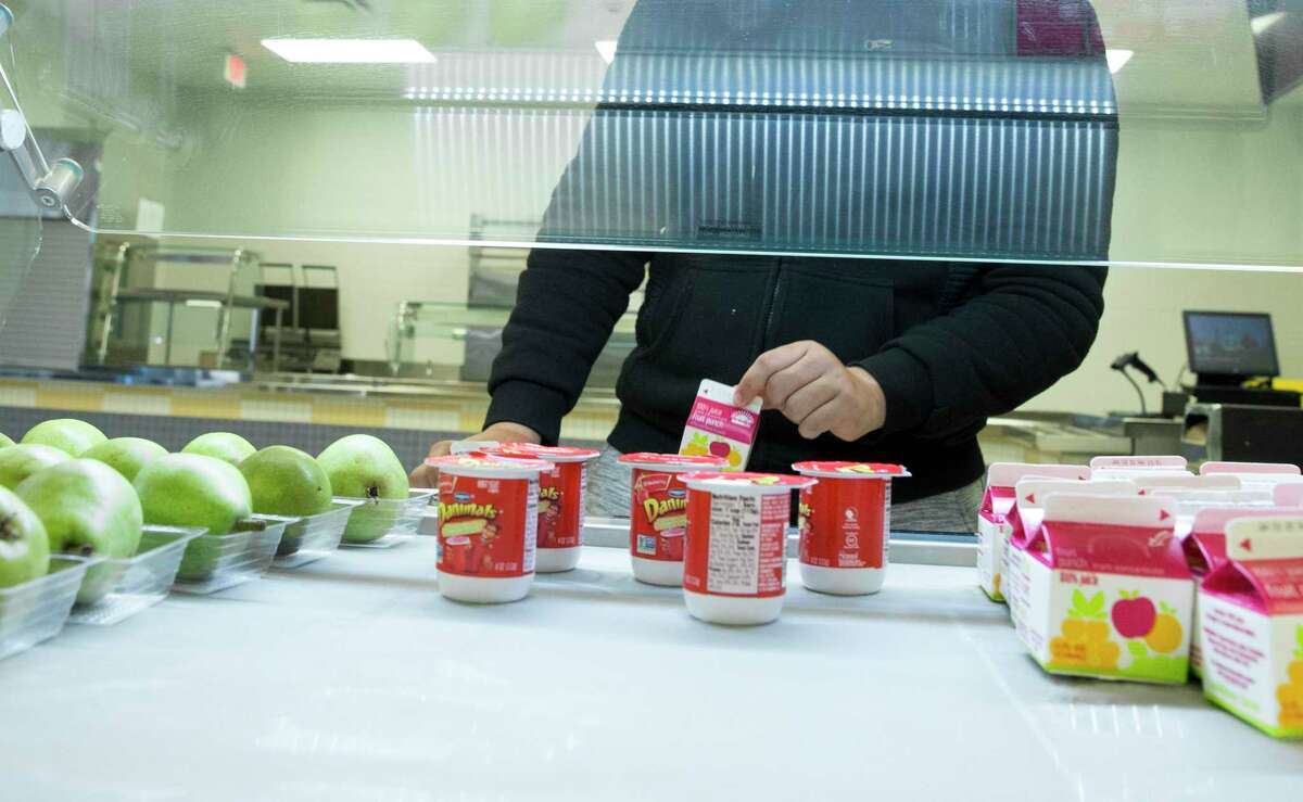 Booker T. Washington High School student Luis Perez, 16, picks up a fruit juice for his breakfast at no cost, as part of the Houston Independent School District's efforts to feed kids during the holiday break, on Monday, Dec. 23, 2019, in Houston. The breakfast offered milk, breakfast bar, fruit, fruit juice and yogurt.