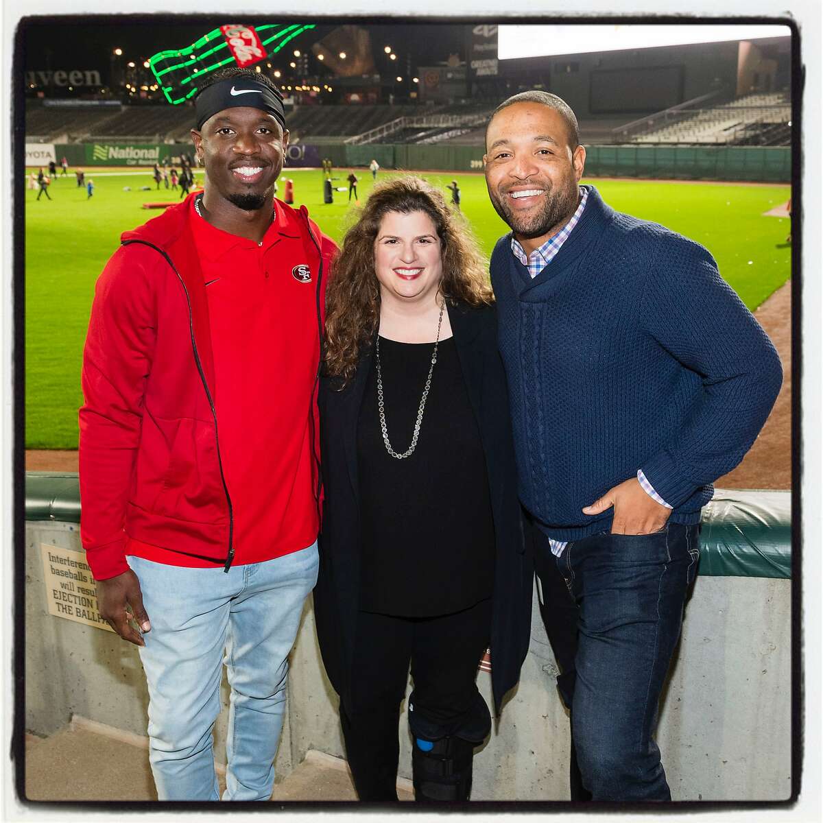49er Jaquiski Tartt (left) with Amy Wender-Hoch and 49ers Foundation executive director Justin Prettyman at Oracle Park during Holiday Heroes. Dec. 10, 2019.