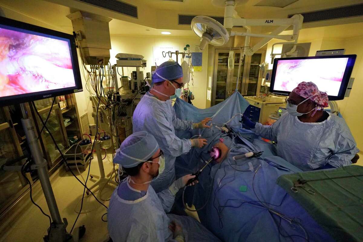 Dr. Chris Tallman, left, Dr. Richard Link, and Gwen Williams, surgical technologist, right, work during laparoscopic surgery to remove a kidney from patient Tina Johnson at Houston Methodist Hospital Tuesday, Dec. 17, 2019, in Houston. Johnson’s kidney is being donating to Brenda Rangel.