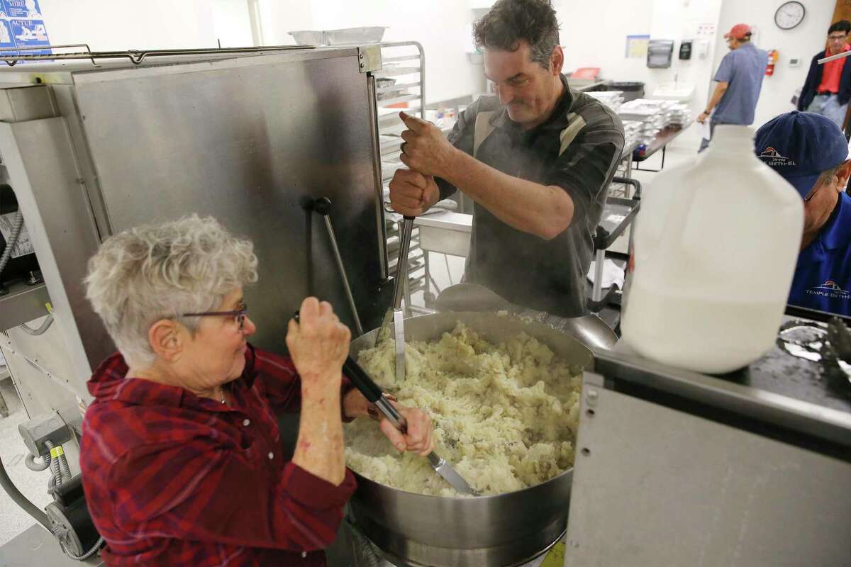 Ann Winer (from left) and Dan Klein whip up mashed potatoes Wednesday so other volunteers from the Jewish congregation of Temple Beth-El could deliver meals to first responders working on Christmas Day at 55 police and fire stations across Bexar County.