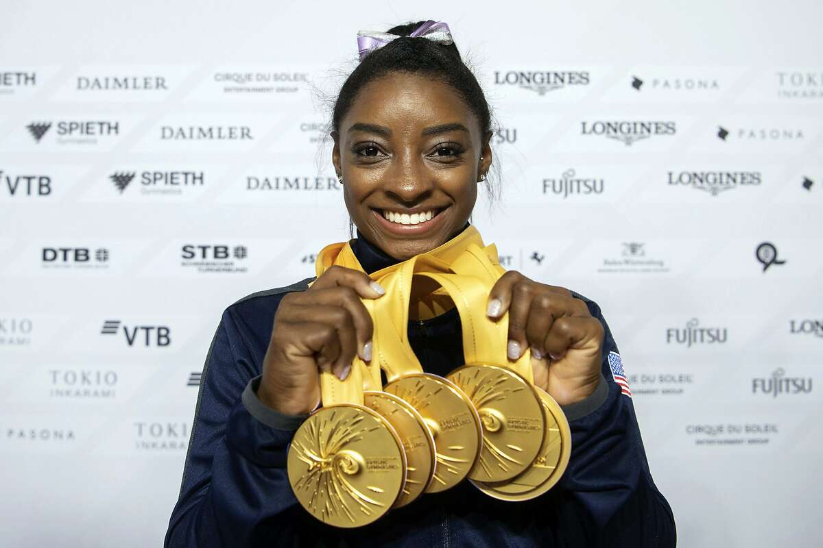 File-This Oct. 13, 2019, file photo Simone Biles of the United States shows her five gold medals at the Gymnastics World Championships in Stuttgart, Germany. Biles is the 2019 AP Female Athlete of the Year. She is the first gymnast to win the award twice and the first to win it in a non-Olympic year. (Marijan Murat/dpa via AP, File)
