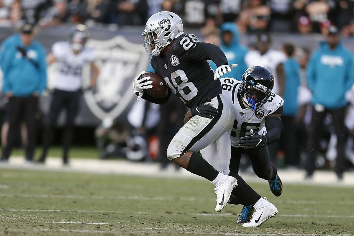Oakland Raiders running back Josh Jacobs runs with the ball around Jacksonville Jaguars free safety Jarrod Wilson (26) during the second half of an NFL football game in Oakland, Calif., Sunday, Dec. 15, 2019. Jacksonville won the game 20-16. (AP Photo/D. Ross Cameron)