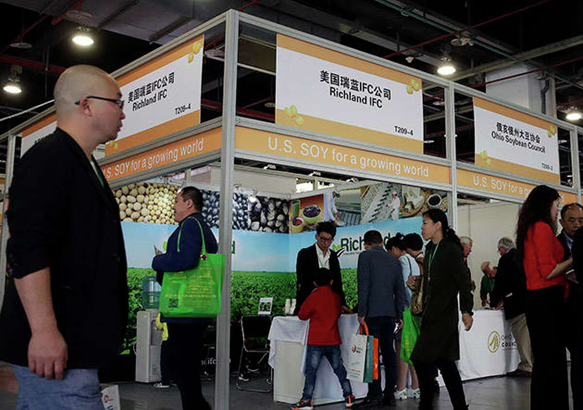 Visitors walk by U.S. soybean companies’ booths at the international soybean exhibition in Shanghai, China. President Donald Trump likes to joke that America’s farmers have a nice problem on their hands: They’re going to need bigger tractors to keep up with surging Chinese demand for their soybeans and other agricultural goods under a preliminary deal between the world’s two largest economies. Yet skeptics are questioning how much China has committed to buy.