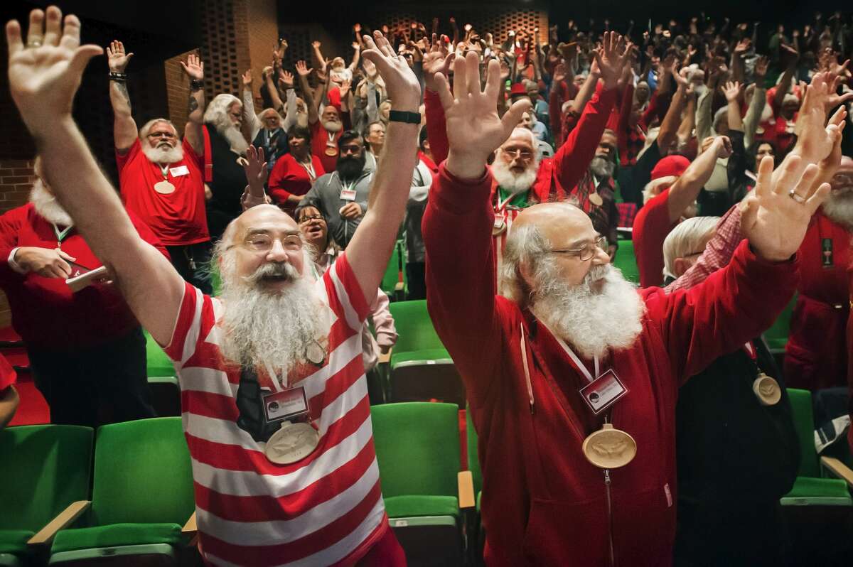 Paul Akert of Wisconsin, left, and Thomas Bethke of Minnesota, right, raise their hands in the air and stretch alongside about 300 of their fellow "Santas" during the 82nd annual Charles W. Howard Santa Claus School Thursday, Oct. 3, 2019 at Midland Center for the Arts. (Katy Kildee/kkildee@mdn.net)