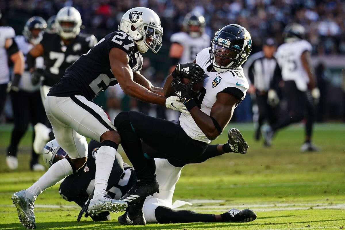 OAKLAND, CALIFORNIA - DECEMBER 15: Chris Conley #18 of the Jacksonville Jaguars is tackled by Trayvon Mullen #27 of the Oakland Raiders after a catch during the second half at RingCentral Coliseum on December 15, 2019 in Oakland, California. (Photo by Daniel Shirey/Getty Images)