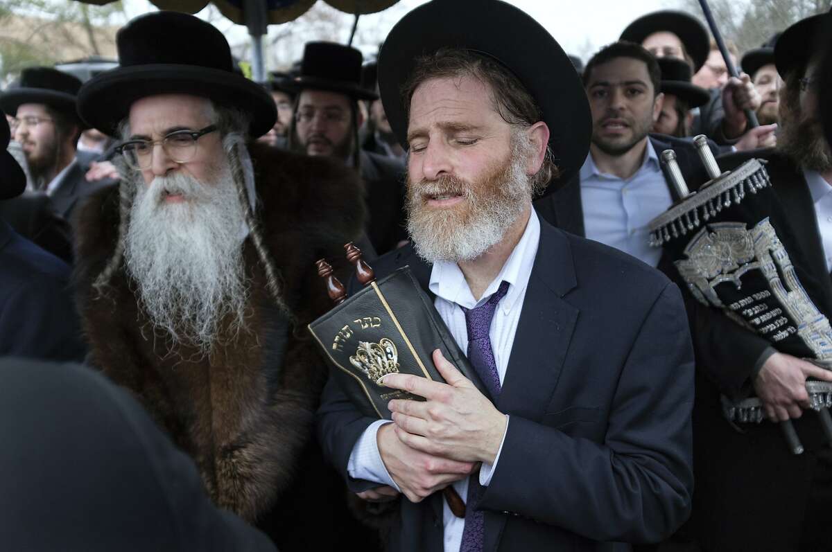 Community members, including Rabbi Chaim Rottenberg, left, celebrate the arrival of a new Torah near the rabbi's residence in Monsey, N.Y. A day earlier, a knife-wielding man stormed into the home and stabbed multiple people as they celebrated Hanukkah in the Orthodox Jewish community. (AP Photo/Craig Ruttle)