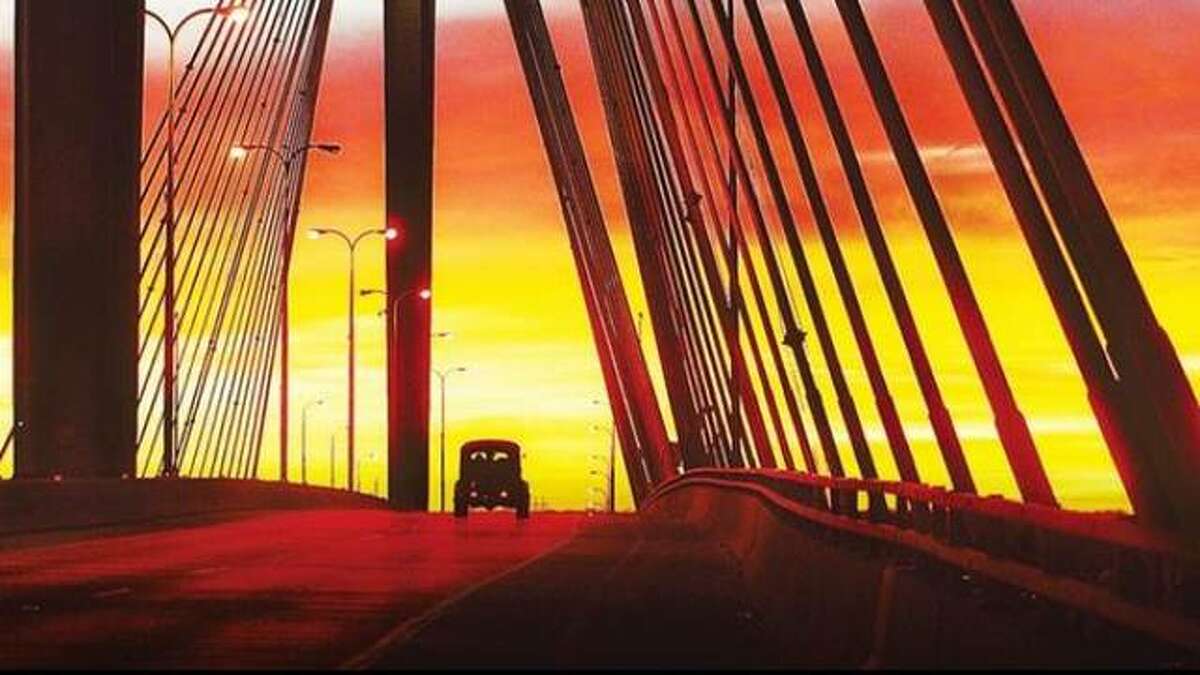 An antique vehicle travels over the Clark Bridge in Alton during sunset.