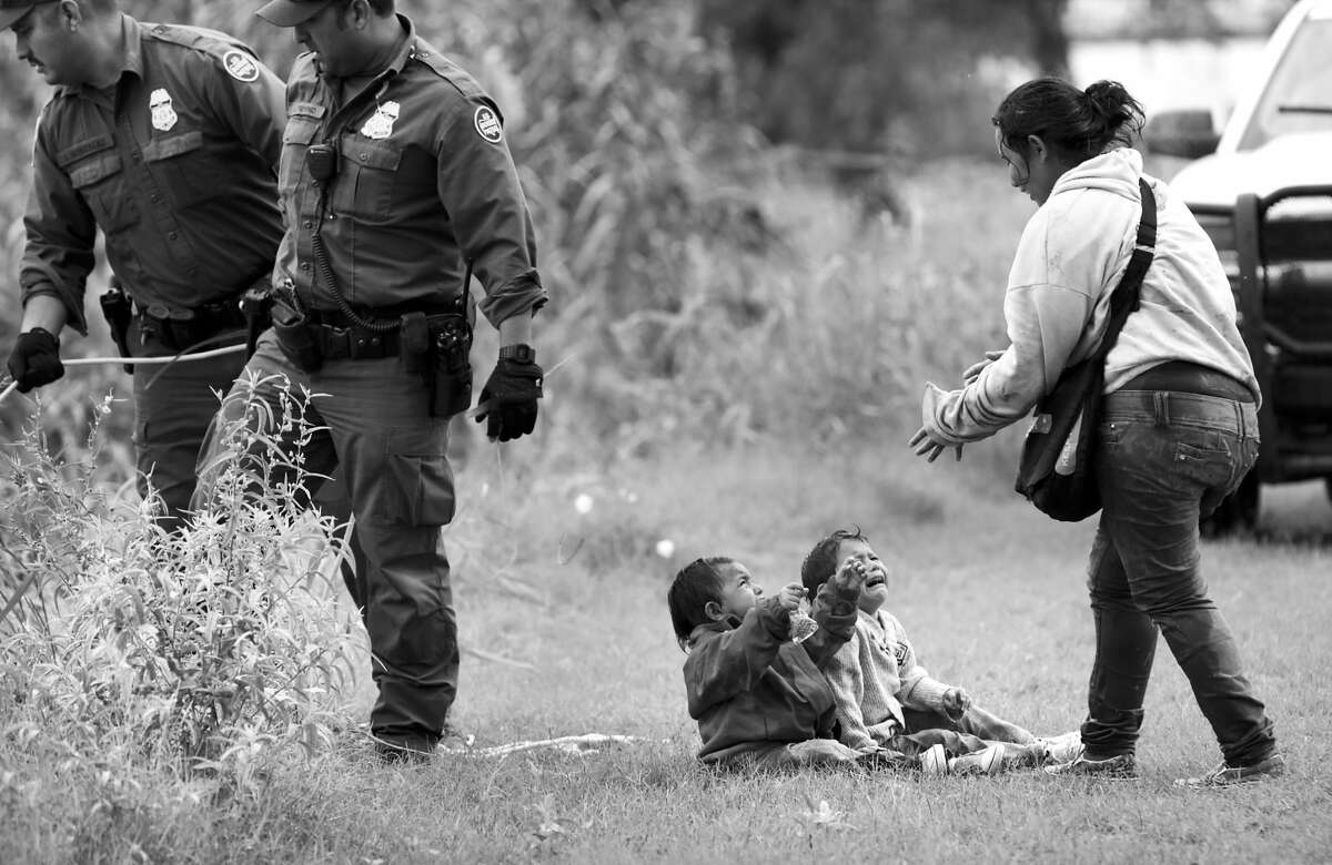 A mother from Honduras goes to her two children, two and four years old, after Border Patrol agents react to three rafts crossing the Rio Grande River in Eagle Pass, on Friday, May 10, 2019.