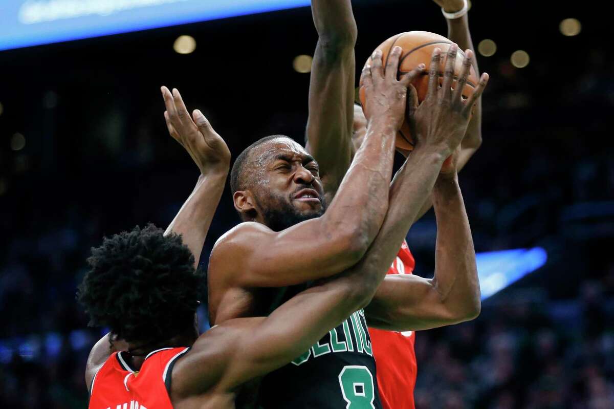 The Toronto Raptors’ OG Anunoby, left, and Chris Boucher, behind, defend against the Boston Celtics’ Kemba Walker on Saturday in Boston.
