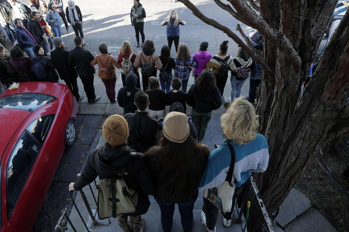 Nicole Deane, with Moms for Housing Solidarity Committee, speaks to supporters forming a human blockade at a home on Magnolia Street in Oakland, Calif., on Monday, December 30, 2019. A judge ordered a continuance to a case involving several mothers with children living in an empty home owned by Wedgewood Properties, a Redondo Beach company, Dominique Walker, a mother to a 1-year-old, moved into a vacant home on Nov. 18 with another Oakland mother, and earlier this month, the corporation that owns the home, delivered an eviction notice. The women - who are homeless - first took over the residence to get shelter and to bring attention to how vacant properties in Oakland are contributing to the homeless crisis.