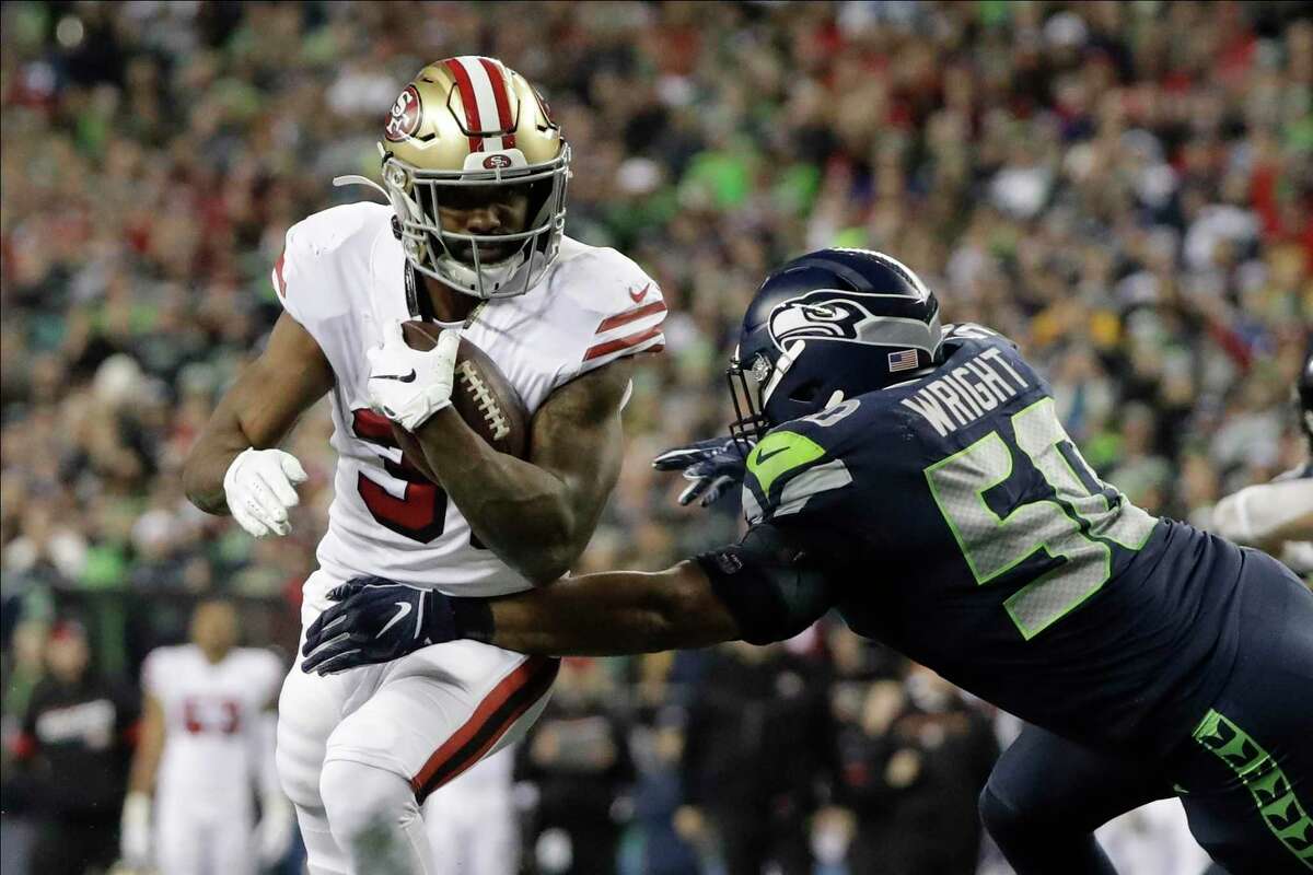 San Francisco 49ers running back Raheem Mostert, left, heads to the end zone to score against the Seattle Seahawks during the second half of an NFL football game, Sunday, Dec. 29, 2019, in Seattle. An average of 23.3 million viewers watched the game, which was shown on NBC.