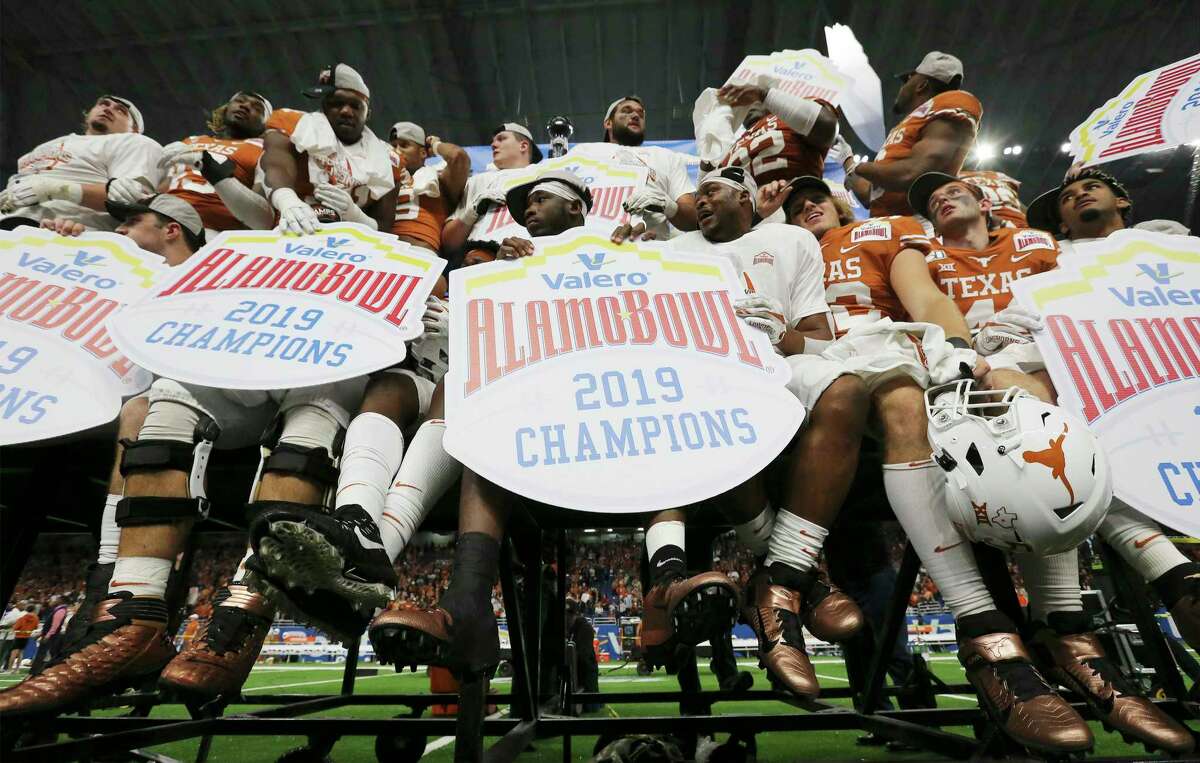 Texas Longhorn players hold Alamo Bowl signs after they defeat the Utah Utes at the 2019 Valero Alamo Bowl at the Alamodome on Tuesday, Dec. 31, 2019. The Longhorns defeated the Utes, 38-10, to win the 2019 Valero Alamo Bowl.