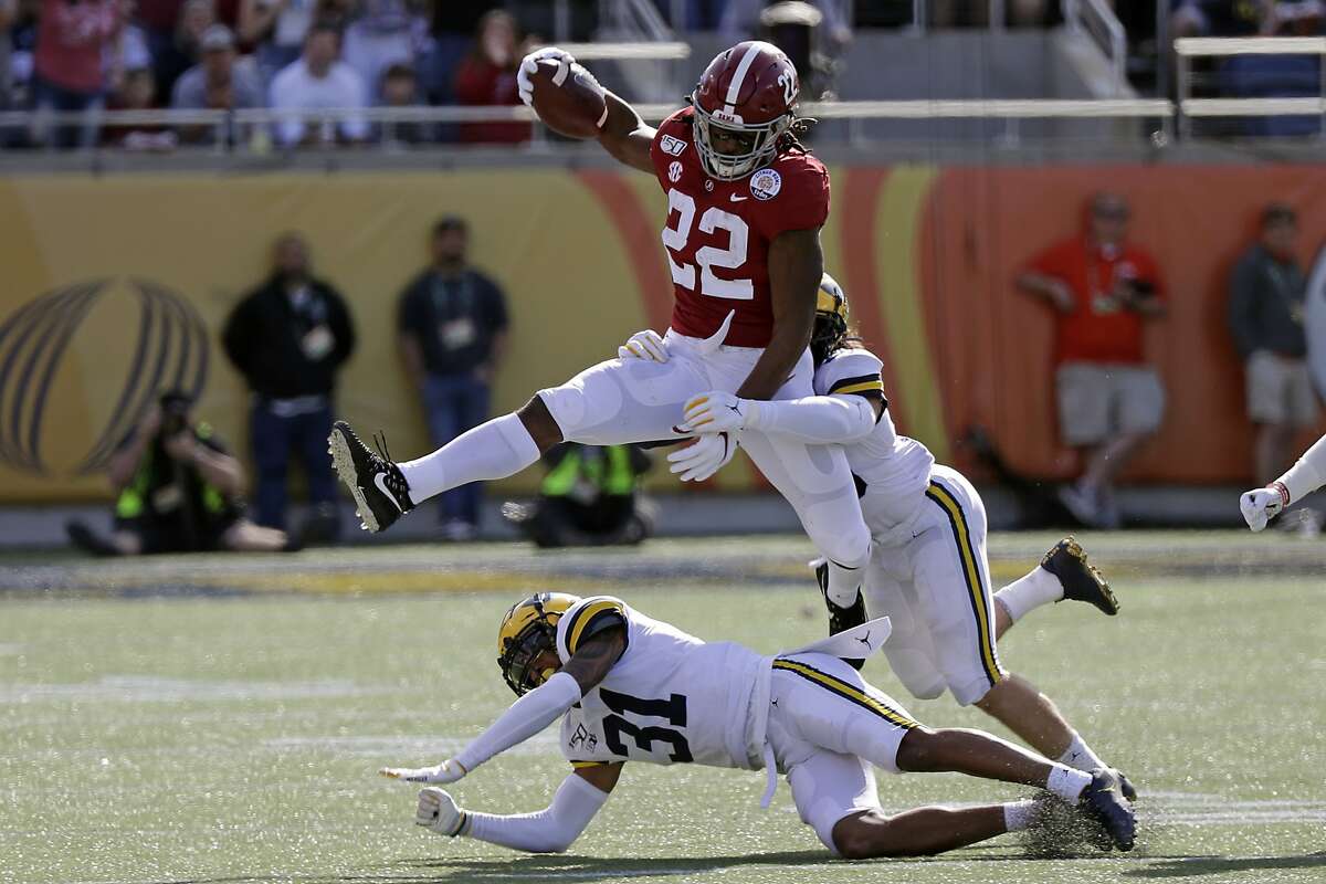 Alabama running back Najee Harris (22) gains yardage as he tries to get past Michigan defensive back Vincent Gray (31) and defensive back DeMarcco Hellams, right, during the first half of the Citrus Bowl NCAA college football game, Wednesday, Jan. 1, 2020, in Orlando, Fla. (AP Photo/John Raoux)