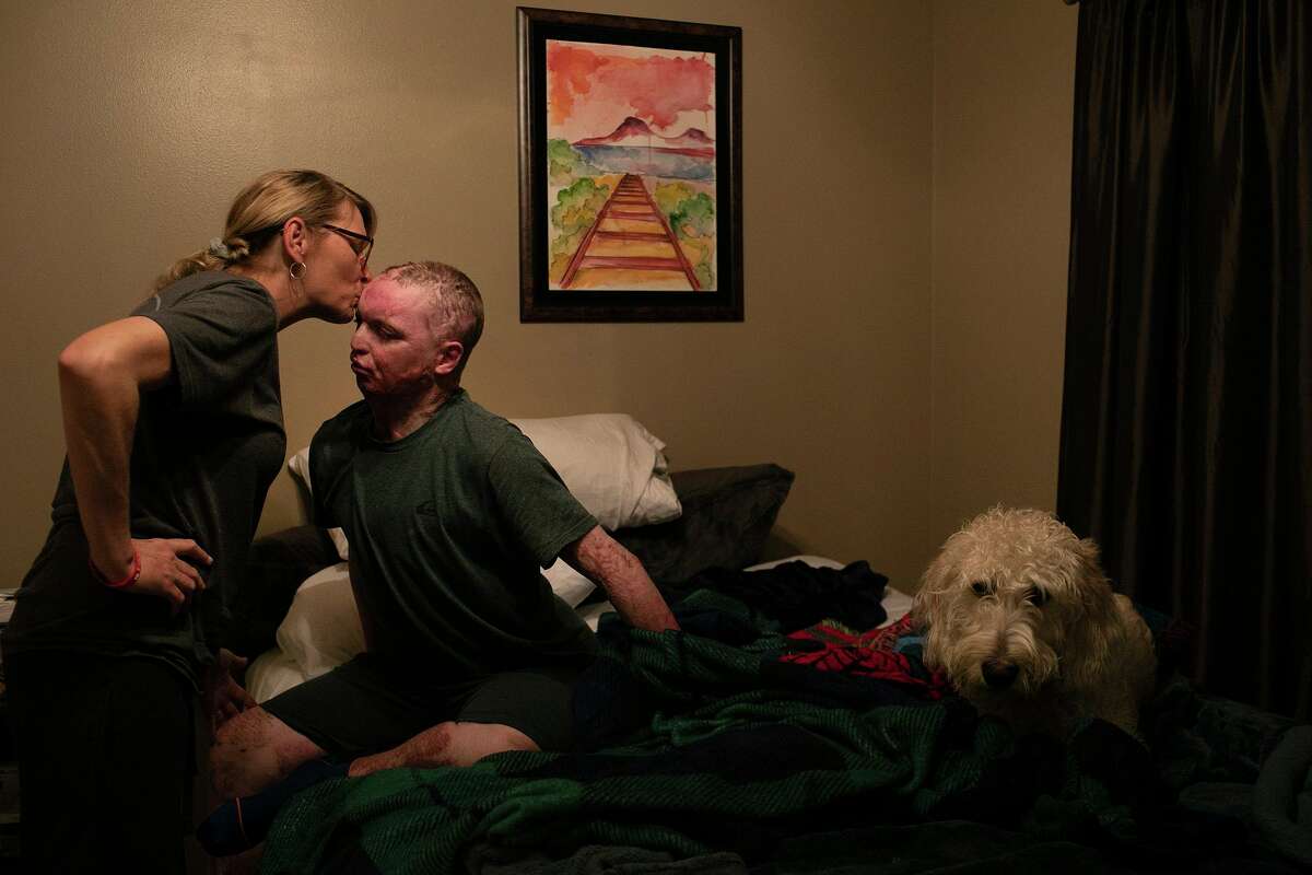 Deona Jo “DJ” Sutterfield gives her son, Zachary, a good night kiss while his service dog, Sketch, waits to snuggle with him at the family’s San Angelo home on Dec. 29. DJ has been at her son’s side since the day he suffered critical injuries in a deadly apartment fire.