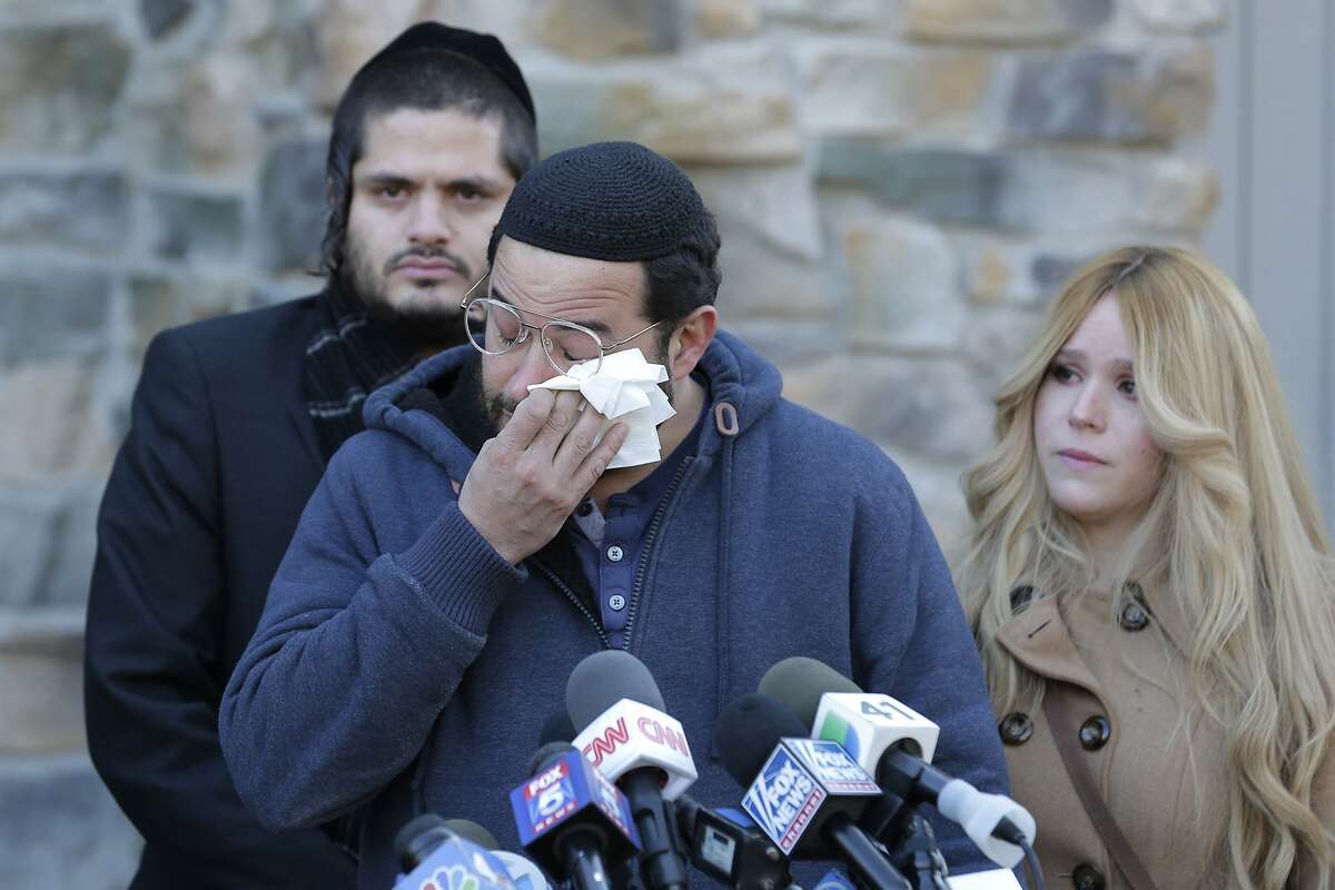 Surrounded primarily by family, David Neumann, center, wipes his eyes as he speaks to reporters in New City, N.Y., Thursday, Jan. 2, 2020, about his father, Josef Neumann who was critically injured in an attack on a Hanukkah celebration. Nicky Cohen, Josef Neumann's daughter, told reporters she hopes her father regains consciousness and finds a changed world while making an emotional plea to end hatred and anti-Semitism. Their 72-year-old father has been unconscious since he was wounded Saturday in a machete attack at a rabbi's home in Monsey, N.Y.