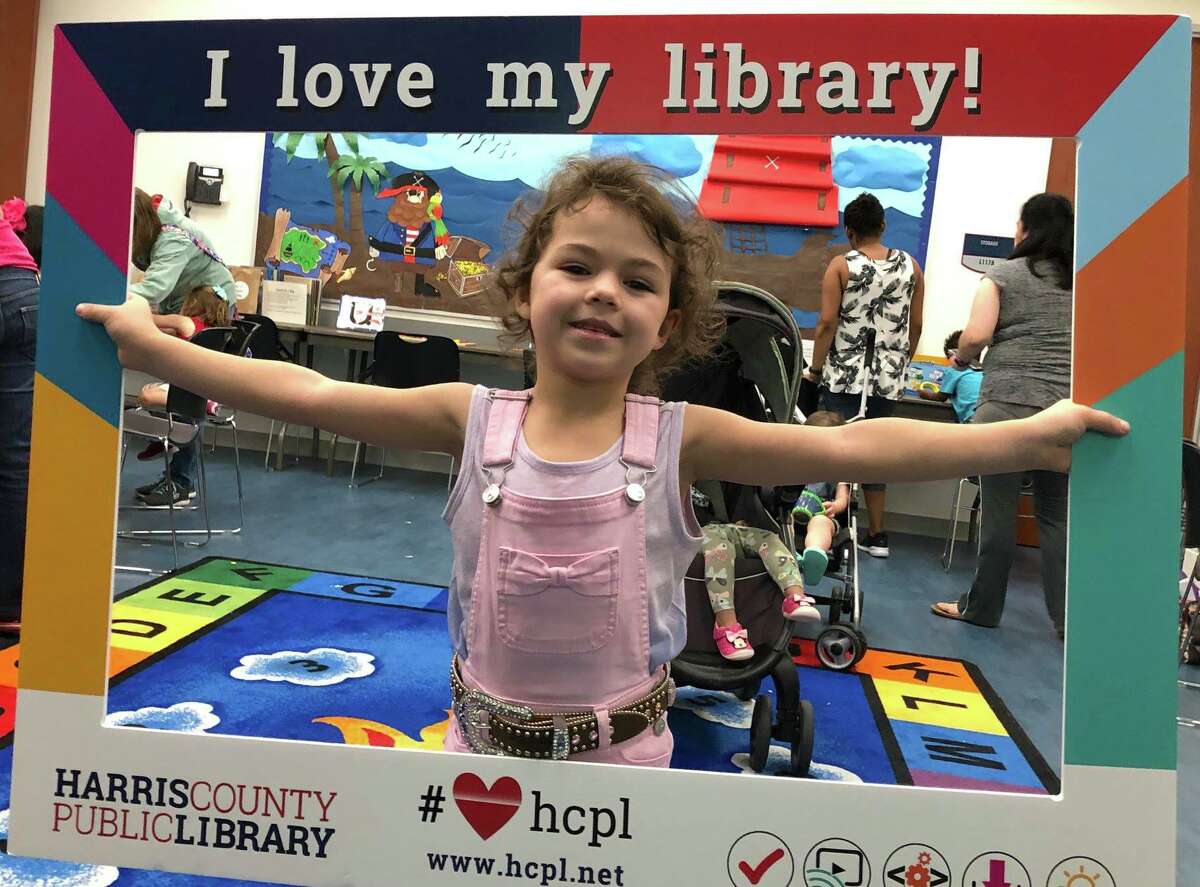 Library patron Debbie Huffstutler's granddaughter poses for a photo at LSC-Tomball Community Library where she developed a love of reading.