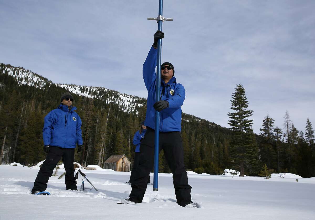 Sean de Guzman, right, chief of snow surveys for the California Department of Water Resources, plunges a snow survey tube into the snowpack during the first snow survey of the season at Phillips Station near Echo Summit, Calif., Thursday, Jan. 2, 2020. The survey found the snowpack at 33.5 inches deep with a water content of 11 inches which is 97% of average at this location at this time of year. Also seen are DWR's Ramesh Gautam, left, and Lauren Miller, behind de Guzman. (AP Photo/Rich Pedroncelli)