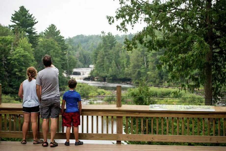 A family takes in the scenic Lower Falls at Tahquamenon Falls State Park in the eastern Upper Peninsula, among the many memory-making destinations in Michigan state parks. (Michigan DNR/Courtesy Photo) / © 2018 State of Michigan