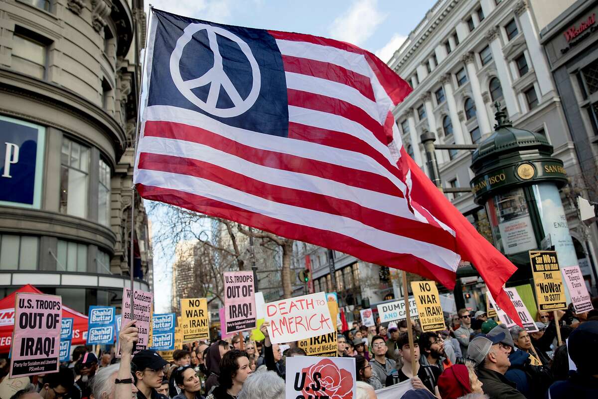 A large American flag with a peace sign waves above the crowd during an anti-war rally in San Francisco , Calif. Saturday, Jan. 4, 2020 in wake of a recent U.S. drone strike that killed a prominent Iranian general in Baghdad.