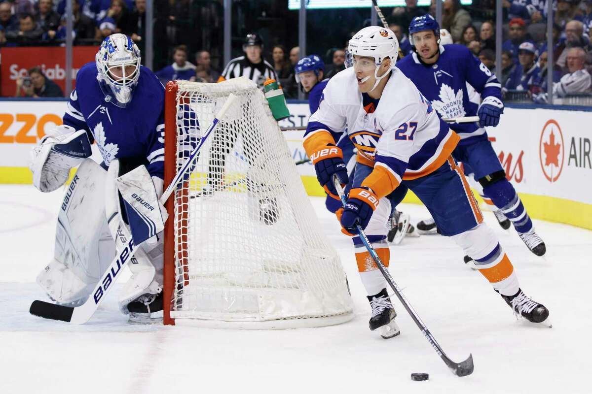 New York Islanders left wing Anders Lee (27) swings the puck around Toronto Maple Leafs goaltender Michael Hutchinson (30) during first period of an NHL hockey game Saturday, Jan. 4, 2020, in Toronto. (Cole Burston/The Canadian Press via AP)