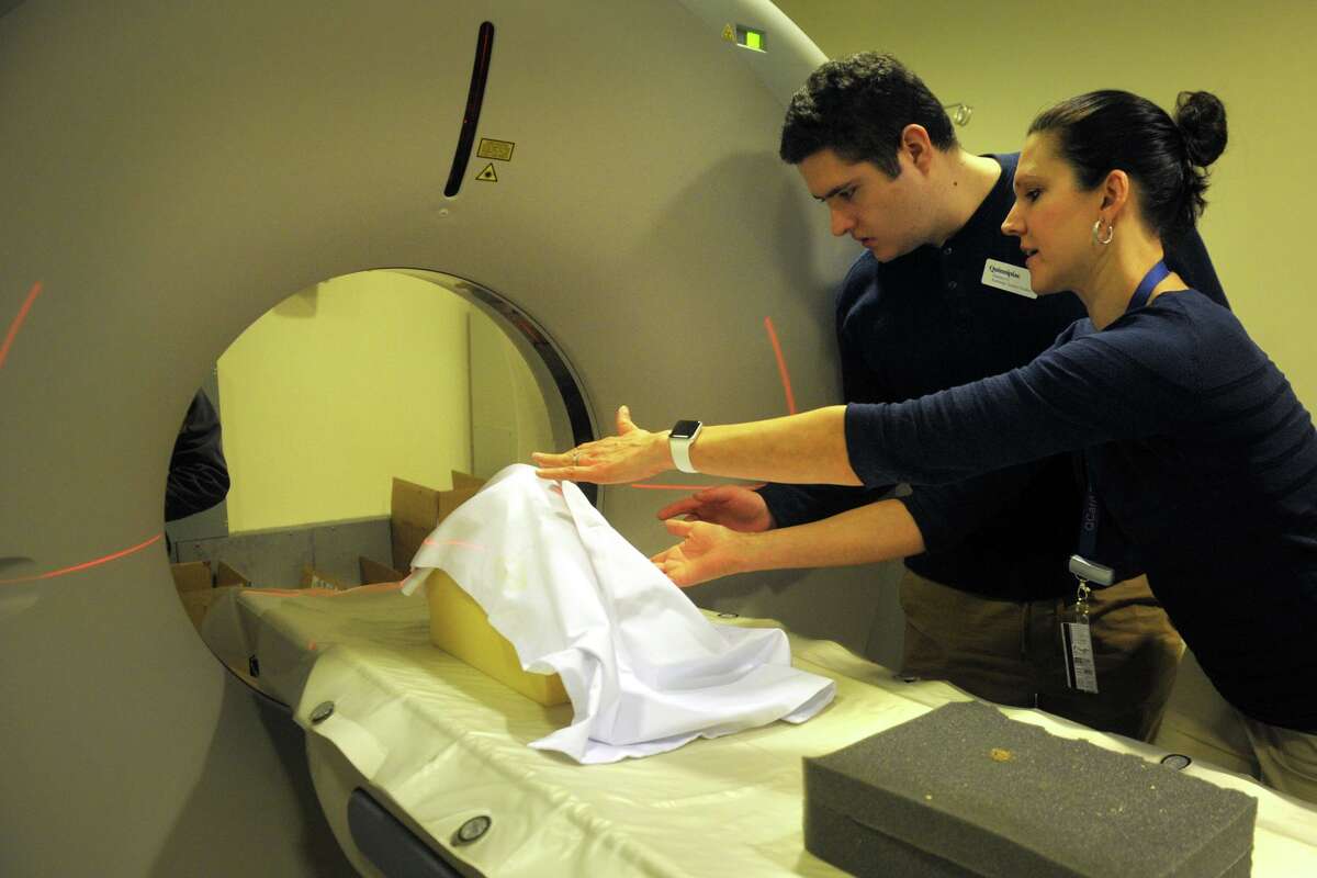 Tania Grgurich, right, clinical associate professor of diagnostic imagining, places a recentlty unearthed human skull, seen here covered by a cloth, into position in preparation for a CT scan at Quinnipiac University. She works with science student Zachary Gurahian, of Westport.