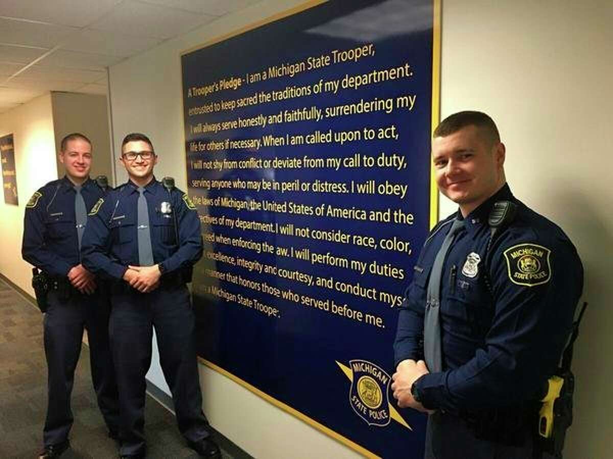 Troopers Rodney Hawkins, Victor Arroyo III and Justin Hanson pose for a photo inside the Caro post next to the Trooper's Pledge. (Lt. Brian McComb/Courtesy Photo)
