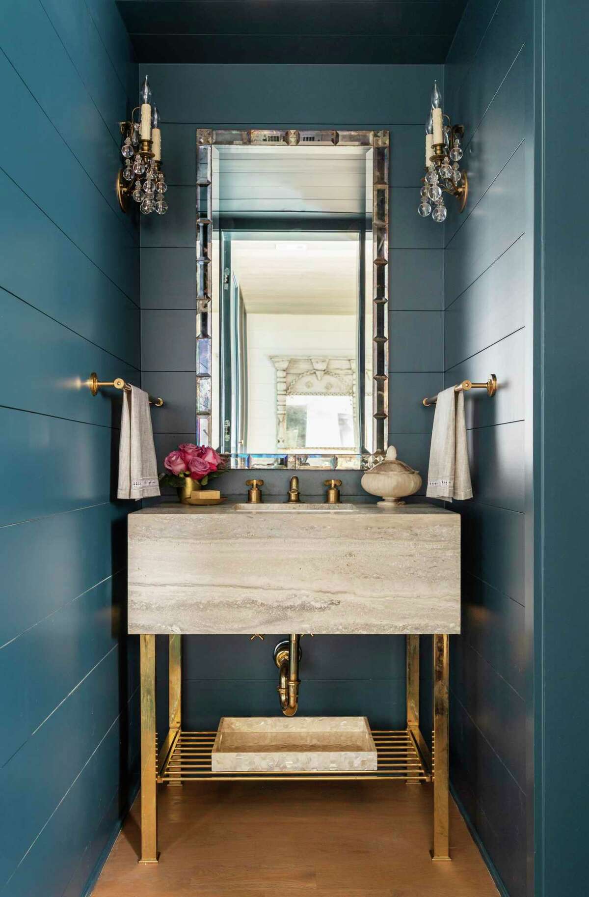 Having a signature, or distinctive, look is part of decorating your home to your personality, says Eyles. This powder/ bathroom was painted teal and outfitted with a marble vanity on a gold-leafed metal base. Sconces and a distinctive mirror finish the look. It was designed by Eyles.