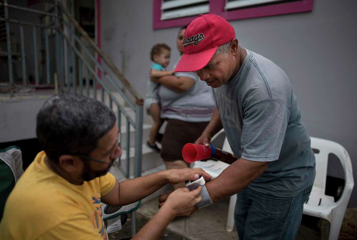 Freddy Martinez, right, borrows a blood pressure monitor from Ruben Rodriguez Quiles after an earthquake hit Guanica, Puerto Rico, Monday, Jan. 6, 2020. A 5.8-magnitude quake hit Puerto Rico before dawn Monday, unleashing small landslides, causing power outages and severely cracking some homes.