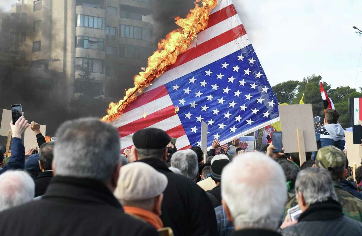 Syrian demonstrators burn the US flag as they gather in the central Saadallah al-Jabiri square in the northern Syrian city of Aleppo on January 7, 2020, to mourn and condemn the death of Iranian military commander Qasem Soleimani, and nine others in a US air strike in Baghdad. (Photo by - / AFP) (Photo by -/AFP via Getty Images)