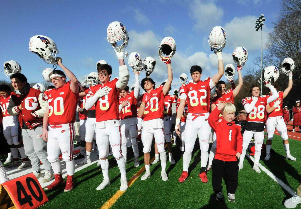 Greenwich's Ben McFadden, a Cardinal Super Fan sporting a jersey with the #1, joins with players on the field as the raise their helmets at the conclusion of the playing of the National Anthem prior to the start of the traditional Thanksgiving Day football game against Staples at Staples Stadium in Westport, Conn. on Nov. 28, 2019. Greenwich defeated Staples 38-14.
